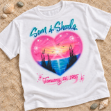 White T-shirt mockup on sand with Sam & Sharla above a pink heart-shaped beach sunset and an optional date below.